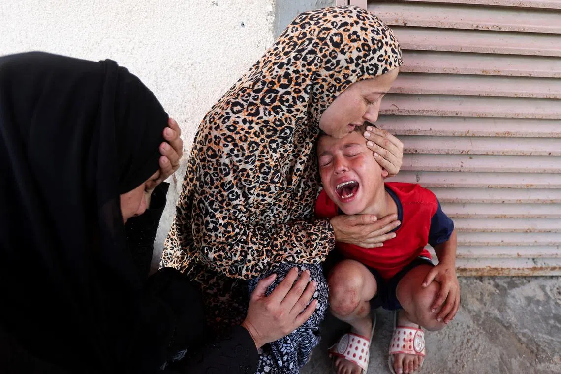 A Palestinian woman comforts a child as casualties are brought into Al-Aqsa Martyrs Hospital following an Israeli strike, in Deir al-Balah, central Gaza Strip, July 10, 2025. REUTERS/Ramadan Abed      TPX IMAGES OF THE DAY
