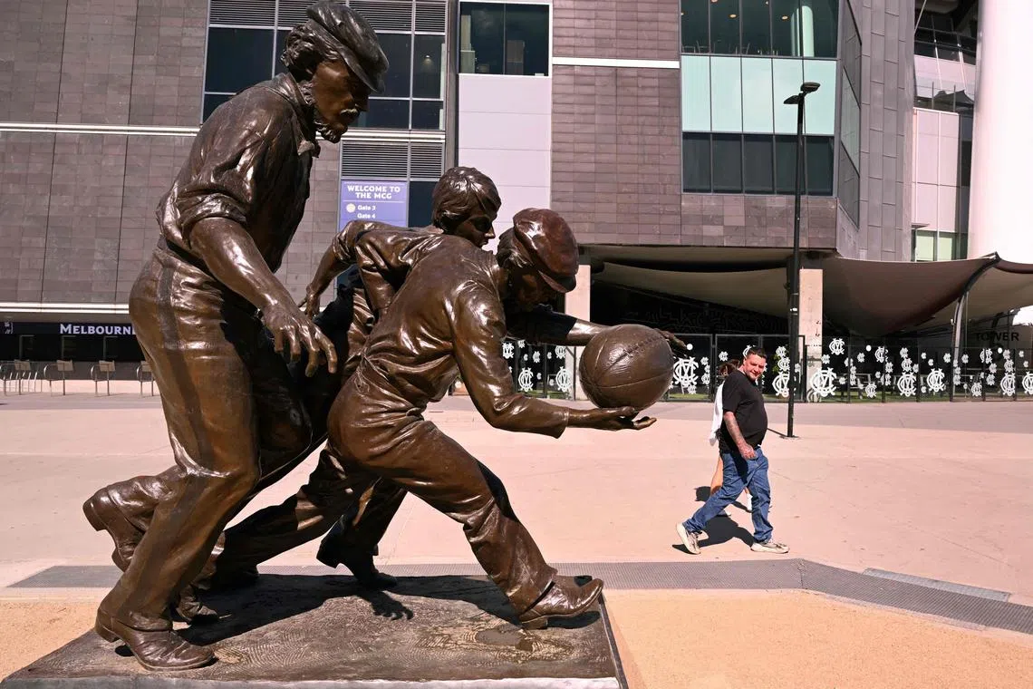 A man looking at a sculpture of original Australian Rules footballers outside the Melbourne Cricket Ground (MCG) on March 27, 2024, after claims of cocaine abuse in the sport were aired by an MP.