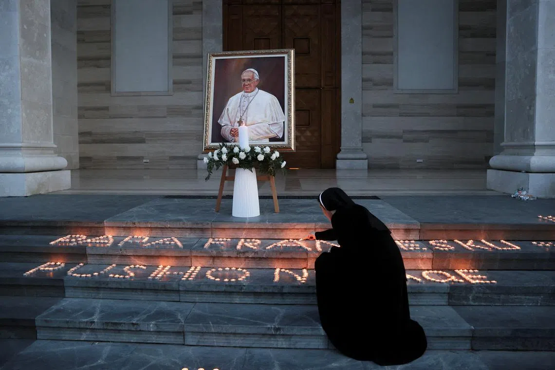 A Catholic nun lights candles following the death of Pope Francis, in front of the Mother Teresa Cathedral in Pristina, Kosovo April 21, 2025. REUTERS/Valdrin Xhemaj