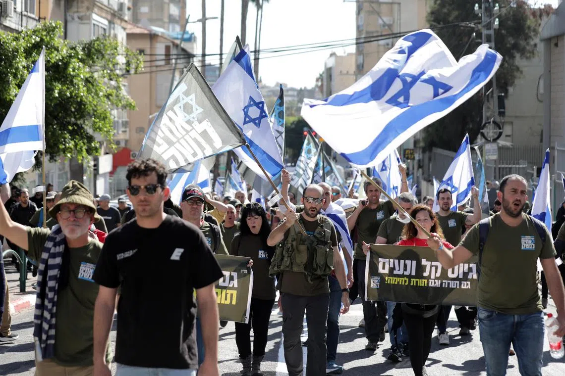 Protesters, including army reservists, waving Israeli flags during a demonstration against the plan to reform Israel's justice system, in Bnei Brak, Israel, on March 16, 2023.