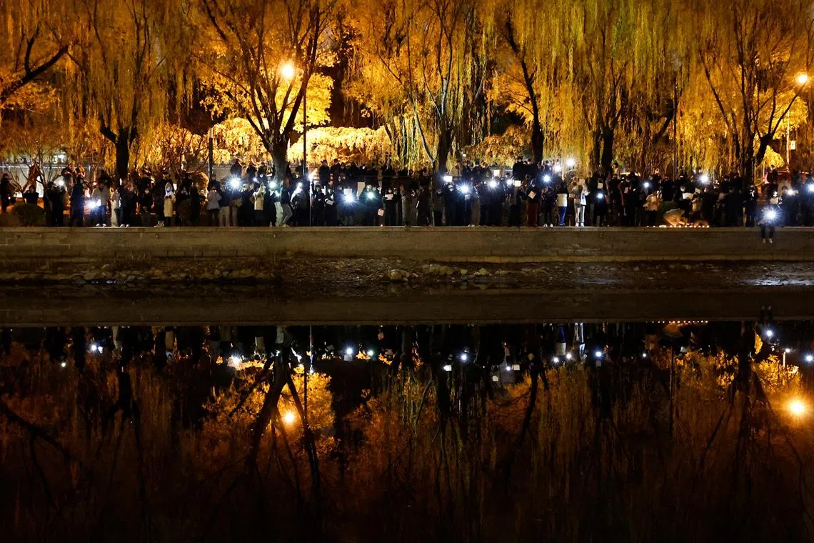 People gather for a vigil and hold white sheets of paper in protest of coronavirus disease restrictions, as they commemorate the victims of a fire in Urumqi, as outbreaks of the coronavirus disease continue in Beijing, China, Nov 27, 2022. 