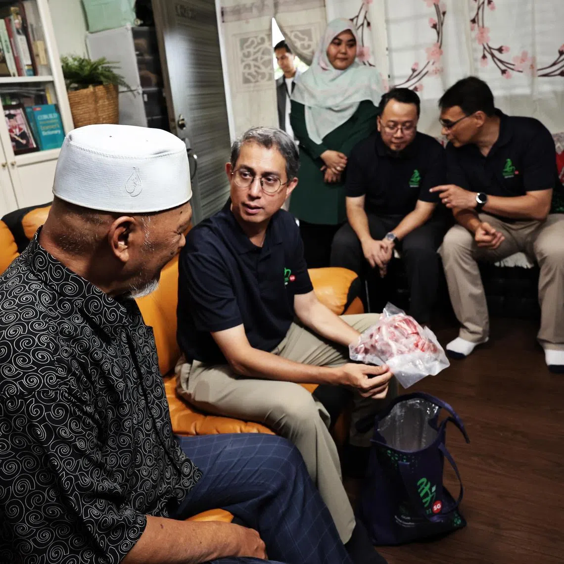 Acting Minister-in-charge of Muslim Affairs Faishal Ibrahim chatting with a resident during a korban meat distribution event on June 28.