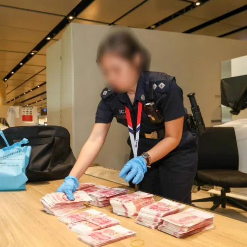 An Immigration and Checkpoints Authority officer conducting checks on a traveller bringing in cash to Singapore during a week-long multi-agency operation.