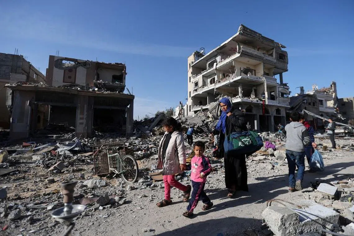 Displaced Palestinians return to their homes as they walk near houses destroyed in an Israeli strike during the conflict, amid the temporary truce between Hamas and Israel, in Khan Younis in the southern Gaza Strip November 24, 2023. REUTERS/Ibraheem Abu Mustafa