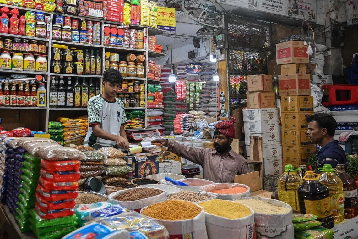 This photograph taken on Jan 21, 2026 shows a shopkeeper attending to customers at a grocery market in Dhaka.