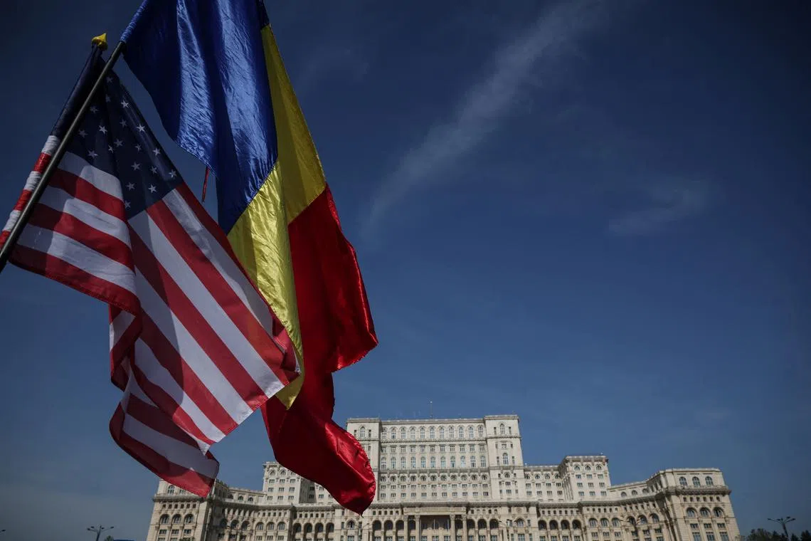 FILE PHOTO: Romanian and U.S. flags flutter near the Palace of the Parliament, following the first round of presidential election in Bucharest, Romania, May 5, 2025. REUTERS/Louisa Gouliamaki/File Photo
