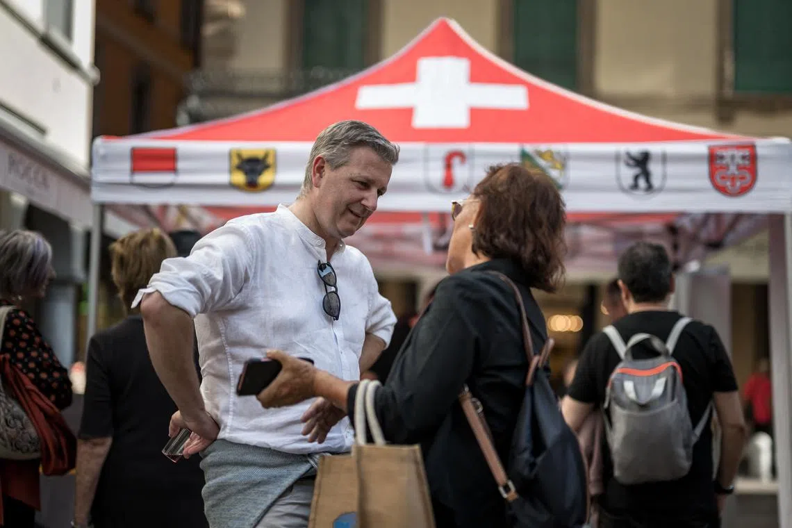 Swiss People's Party leader Marco Chiesa speaking with people at the party's booth in Lugano, southern Switzerland, on Oct 7.