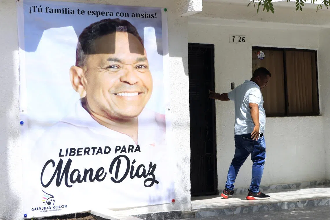 A person leaves the family home of Luis Diaz, where a large poster hangs with the image of his father, Luis Manuel Diaz.