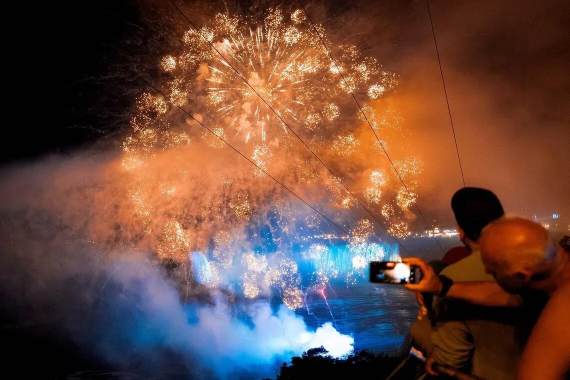 Visitors watching fireworks over an illuminated Niagara Falls, as part of the 11-state landmarks light-up for Game 3 of the NBA Finals between the New York Knicks and San Antonio Spurs, in Niagara Falls, New York, US, June 8.