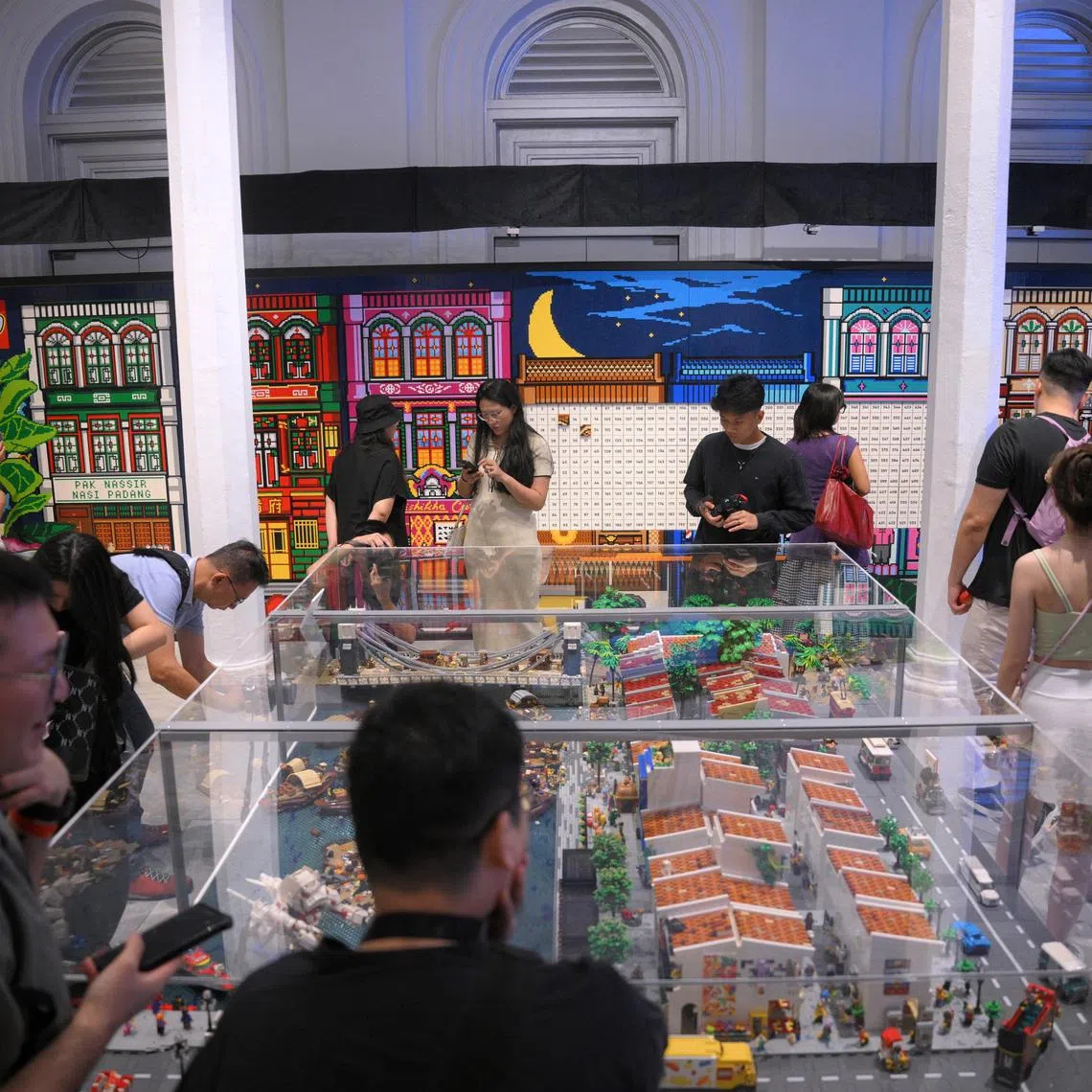 People look at Singapore's largest LEGO Mural (background), set against a LEGO diorama of the Singapore River (foreground),  at the National Museum Singapore on July 17, 2025. The mural was built with over 250,000 LEGO bricks and is part of the Stories of Singapore: Building Our Heritage, Brick by Brick showcase. The mural was officially recognised by the Singapore Book of Records on the same day. Visitors will get access to a total of 528 plates made up of various LEGO bricks, and are invited to add the final bricks to this record-breaking mural.