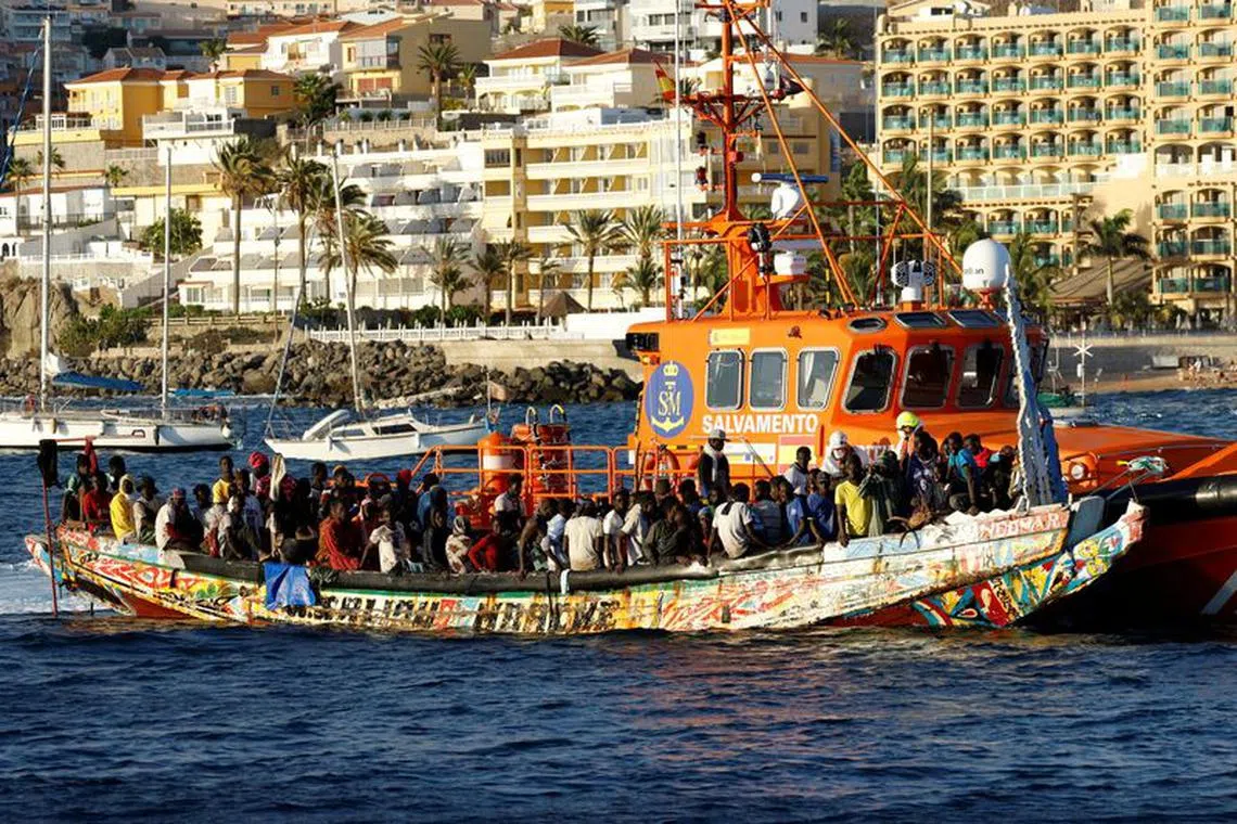 FILE PHOTO: A group of migrants in a wooden boat are towed by a Spanish coast guard vessel to the port of Arguineguin, in the island of Gran Canaria, Spain, October 21, 2023. REUTERS/Borja Suarez/File Photo