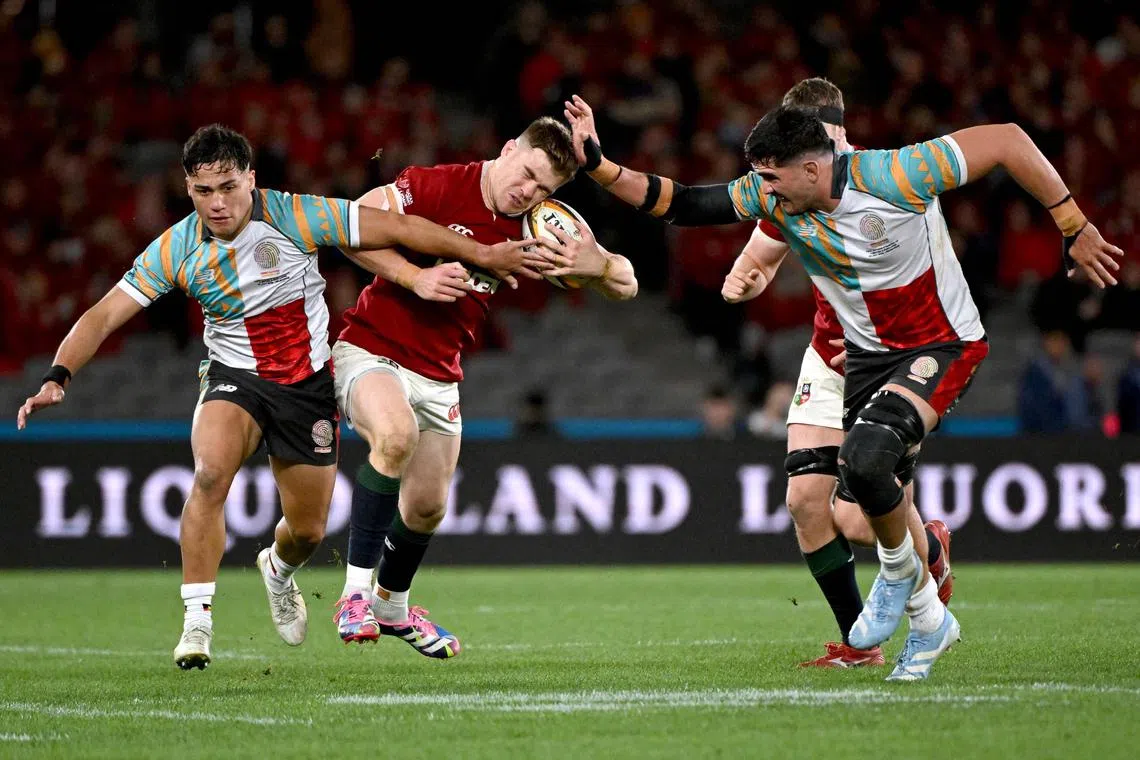 First Nations & Pasifika XV's Darcy Swain and Kalani Thomas tackle British and Irish Lions’ Garry Ringrose.