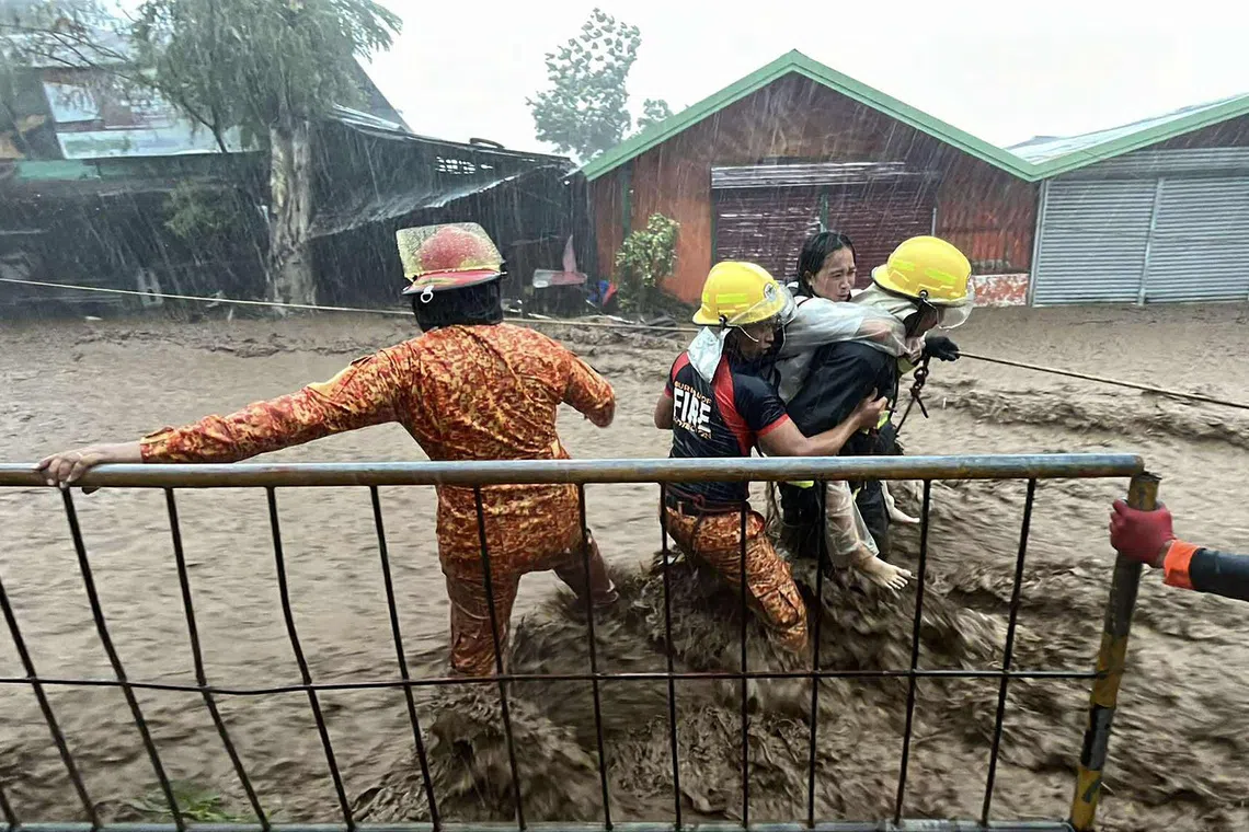 Firemen rescuing a woman amidst surging flood waters due to heavy rains brought about by Typhoon Kalmaegi along a street in Canlaon City, Negros Oriental, Philipines, on Nov 5, 2025.