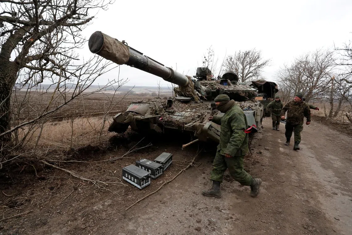 FILE PHOTO: Pro-Russian separatists walk near an abandoned tank on a road between the separatist-controlled settlements of Mykolaivka (Nikolaevka) and Buhas (Bugas), as Russia's invasion of Ukraine continues, in the Donetsk region, Ukraine March 1, 2022. REUTERS/Alexander Ermochenko/File Photo