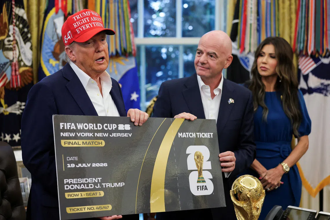 FILE PHOTO: U.S. President Donald Trump and FIFA president Gianni Infantino hold a 2026 FIFA World Cup final match ticket that was presented to President Trump, as the President makes an announcement on the 2026 FIFA World Cup, while U.S. Homeland Security Secretary Kristi Noem stands, in the Oval Office at the White House in Washington, D.C., U.S., August 22, 2025. REUTERS/Jonathan Ernst/File Photo