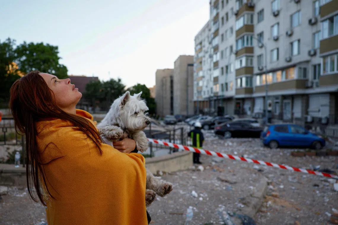 A woman with her dog looking at her apartment building heavily damaged during a massive Russian drone strike, amid Russia's attack on Ukraine, in Kyiv, Ukraine  on May 30, 2023. 