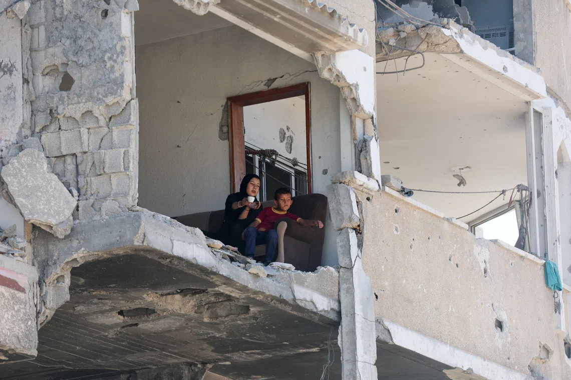 Palestinians sitting in a damaged house, amid a ceasefire between Israel and Hamas in Gaza, in Khan Younis, in the southern Gaza Strip, on Oct 14, 2025. 