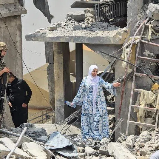 A woman making her way through the rubble on May 27 as a Lebanese soldier looks on at the site of a residential building hit by an Israeli strike near the southern town of Burj al-Shamali, on the outskirts of Tyre.