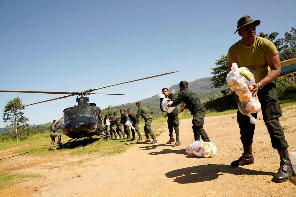 Sri Lanka Army soldiers unload relief material from a helicopter for flood victims in Niyamgamdora, Sri Lanka.