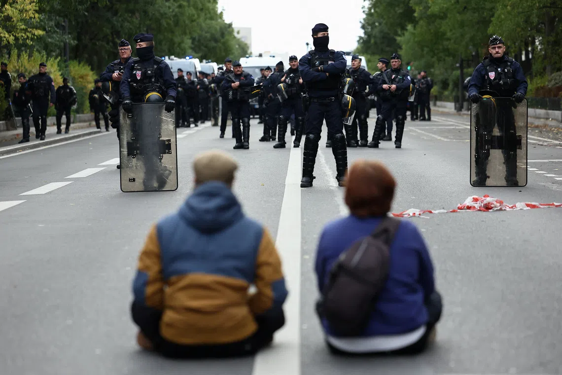 Demonstrators sit in front of officers of the French CRS riot police during a protest organised by student collectives and trade unions in Paris on Oct 22.