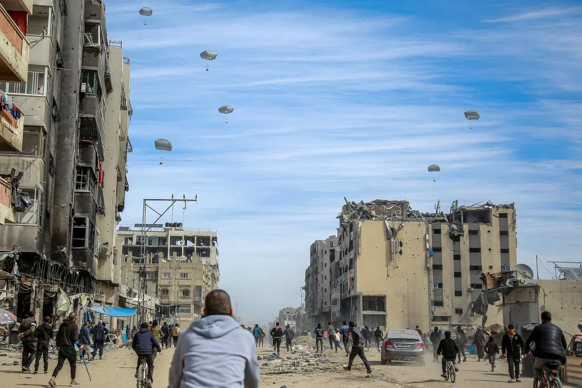 Palestinians running along a street as humanitarian aid is airdropped in Gaza City on March 1, 2024.