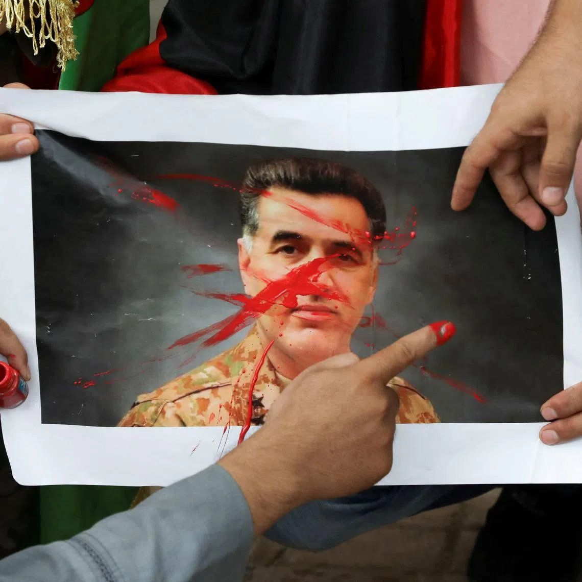 Afghan nationals paint over a picture of Pakistan's Inter-Services Intelligence (ISI) Chief, Lieutenant General Faiz Hameed, as they hold a protest against Pakistan near a police station in New Delhi, India, September 10, 2021. REUTERS/Anushree Fadnavis/File Photo