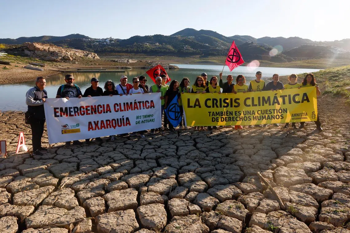 Members of the environmental and human rights organizations hold banner that read, "Climate emergency" and "The climate crisis is also a human rights issue" as they protest on the cracked ground of La Vinuela reservoir in a severe drought, as they call for the defense of natural resources, human rights and protest climate change, during the World Water day in La Vinuela, near Malaga, Spain March 22, 2023. REUTERS/Jon Nazca