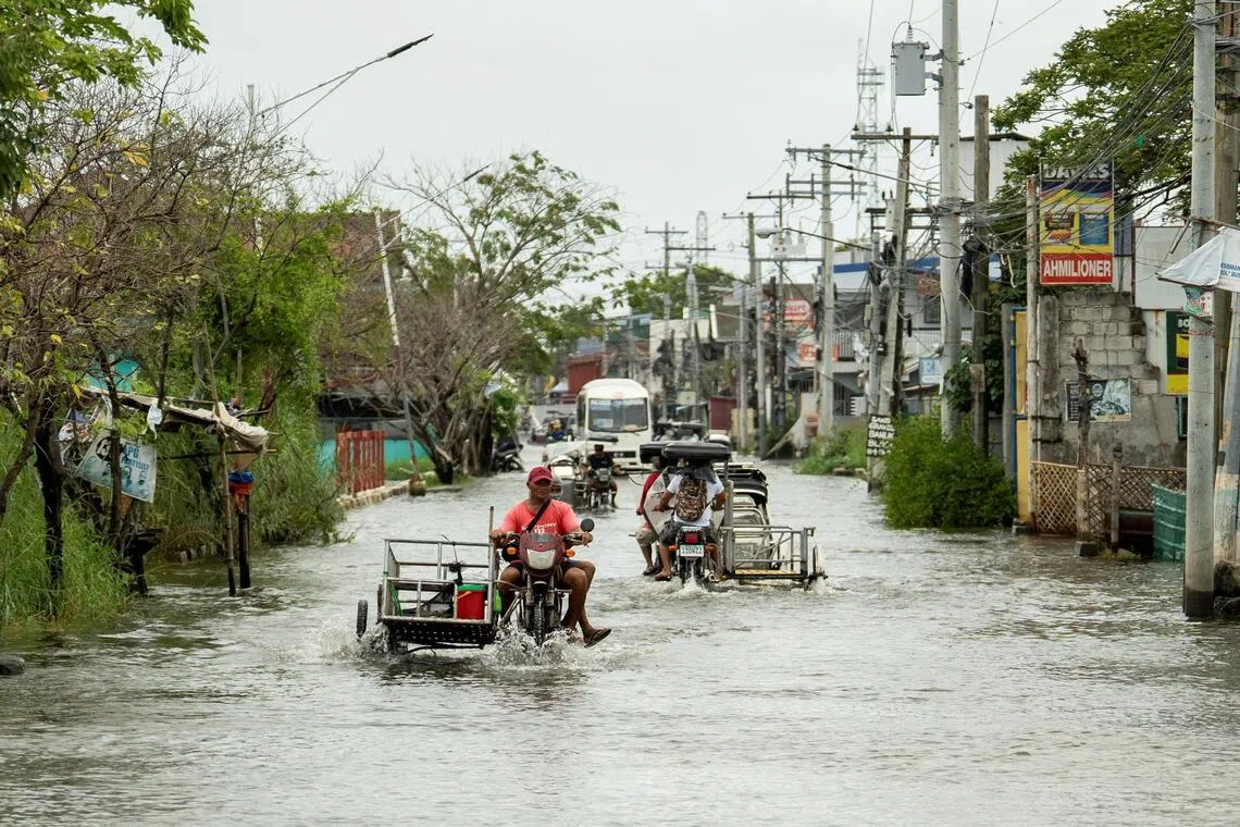 Motorists wade through a flooded road, following heavy rains intensified by Super Typhoon Ragasa, in Apalit, Pampanga province, Philippines, September 23, 2025. REUTERS/Lisa Marie David 