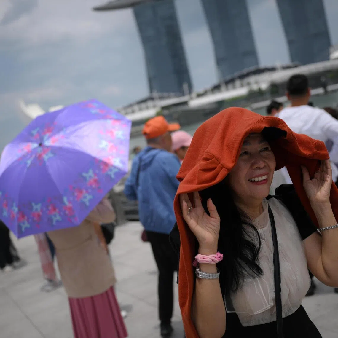 A lady uses a jacket to shield herself from the sun during a hot day at the Merlion Park on March 26.