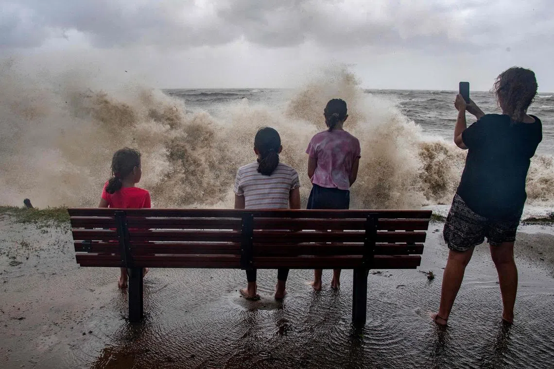 A family watch the storm roll in across the Coral Sea at Holloways Beach as Cyclone Jasper approaches landfall in Cairns.