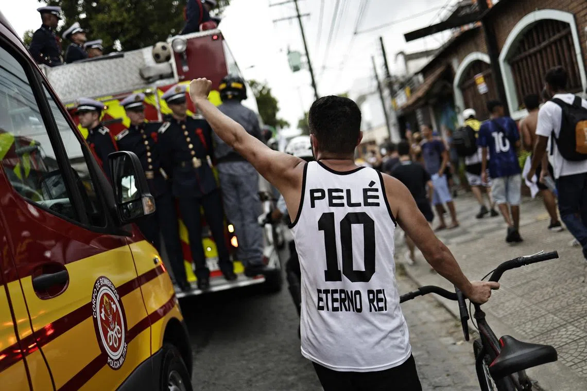 A fan is pictured wearing a Pele shirt as the casket of Brazilian soccer legend Pele passes by, Jan 3, 2023. 