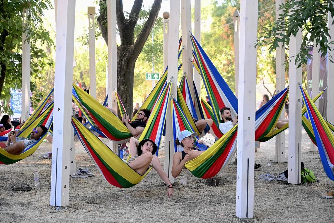 TOPSHOT - People relax on colorful hammocks during the Sziget Festival at Obuda Island, in Budapest, Hungary, on August 13, 2026, The 33rd Sziget Festival will take place from August 11 to 15, 2026. (Photo by Attila KISBENEDEK / AFP)
