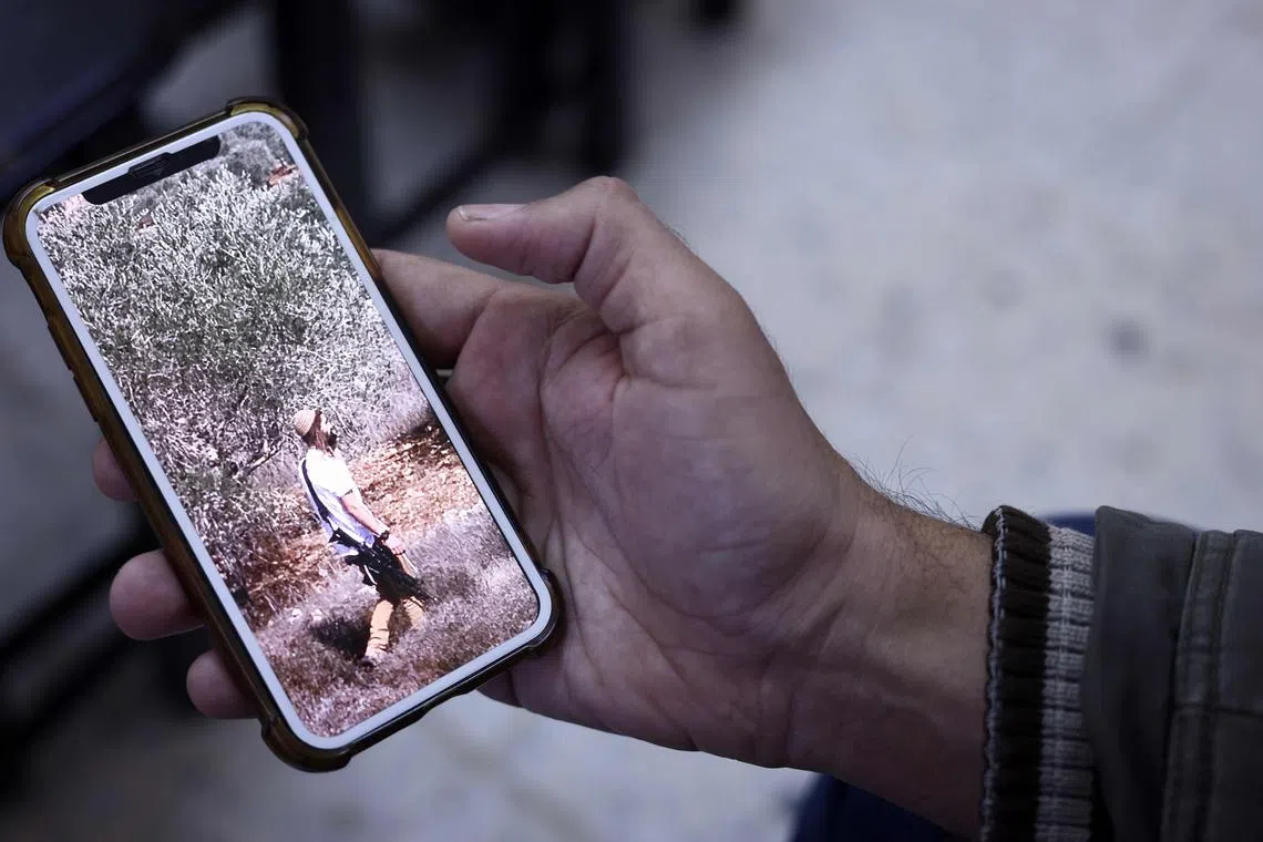 A relative of a Palestinian who was killed amid settler violence shows a picture of an armed Israeli settler, in the occupied West Bank, in November 2023.
