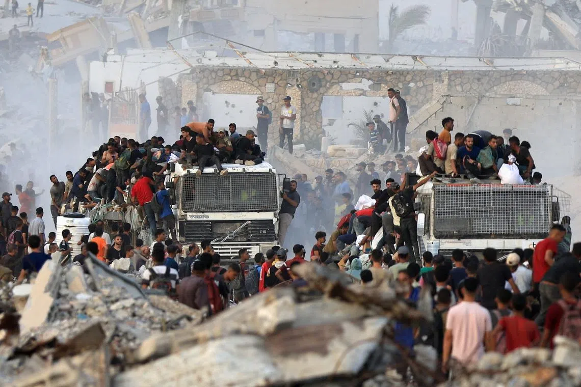 Palestinians climb onto trucks carrying aid supplies that entered Gaza through Israel, in Beit Lahia, in the northern Gaza Strip July 29, 2025. REUTERS/Dawoud Abu Alkas