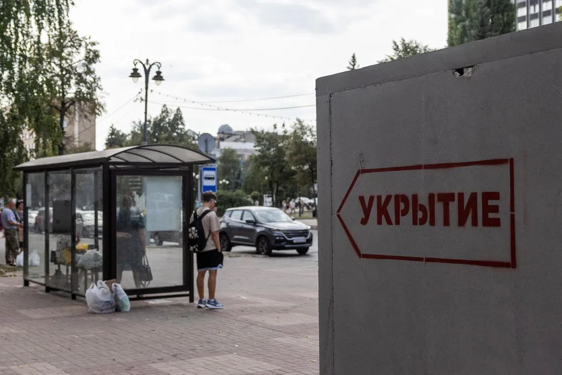 FILE PHOTO: People wait at a bus stop next to a reinforced concrete bomb shelter installed in a street in the course of Russia-Ukraine conflict, in Kursk, Russia August 28, 2024. The sign on the construction reads: \"Shelter\". REUTERS/Maxim Shemetov/File Photo