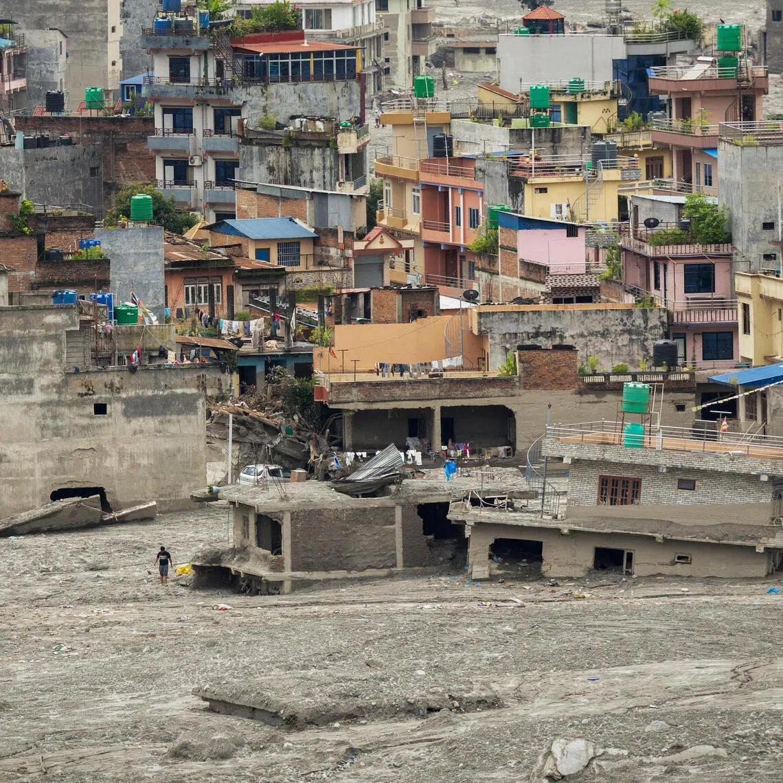 A man walks past damaged houses following the deadly flash floods and a mudslide, in Trishuli, Nuwakot district, in Nepal on Sept 4.