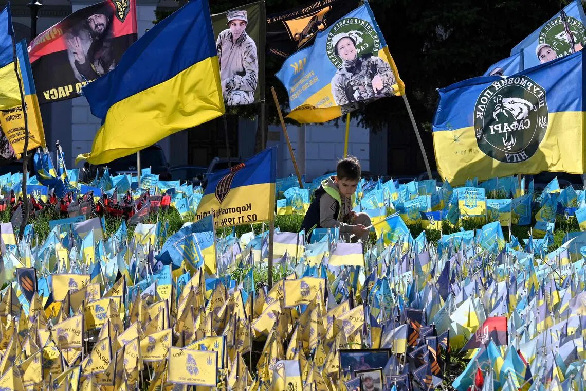 A boy places a flag at a makeshift memorial for fallen Ukrainian soldiers in Kyiv's  Independence Square.