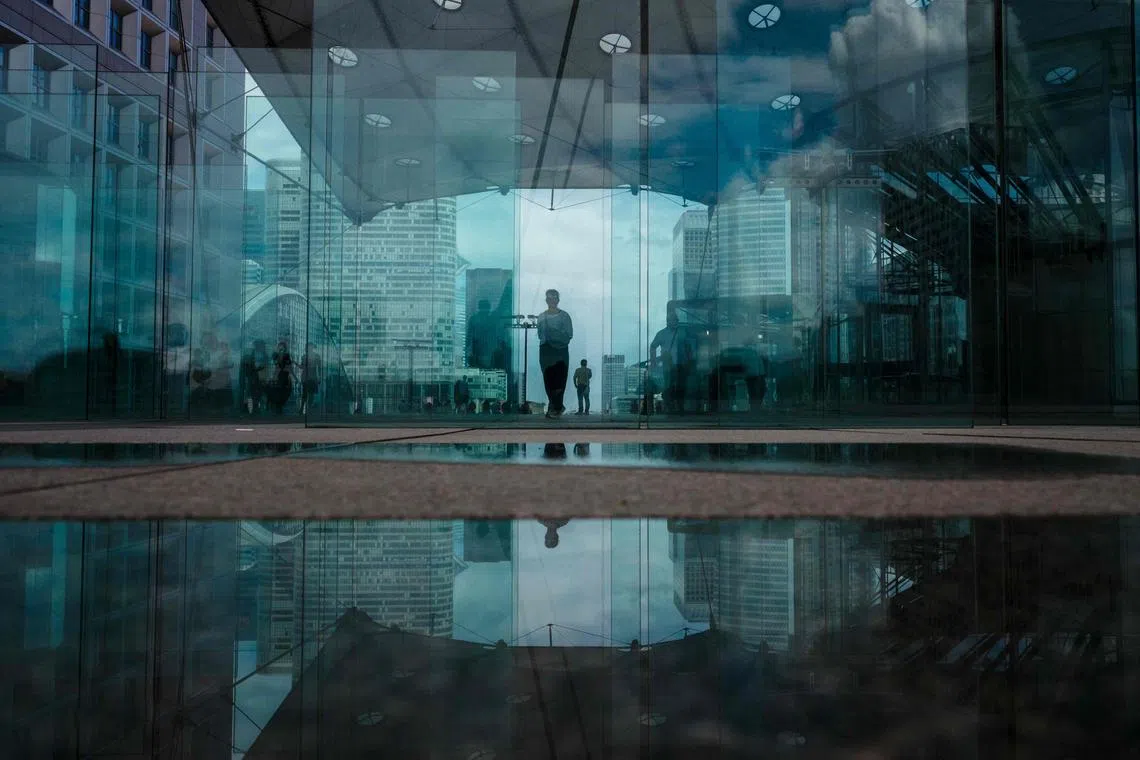 People walking under the Grande Arche de La Defense at the La Defense business district, on the western outskirts of Paris, on July 17, 2025. 