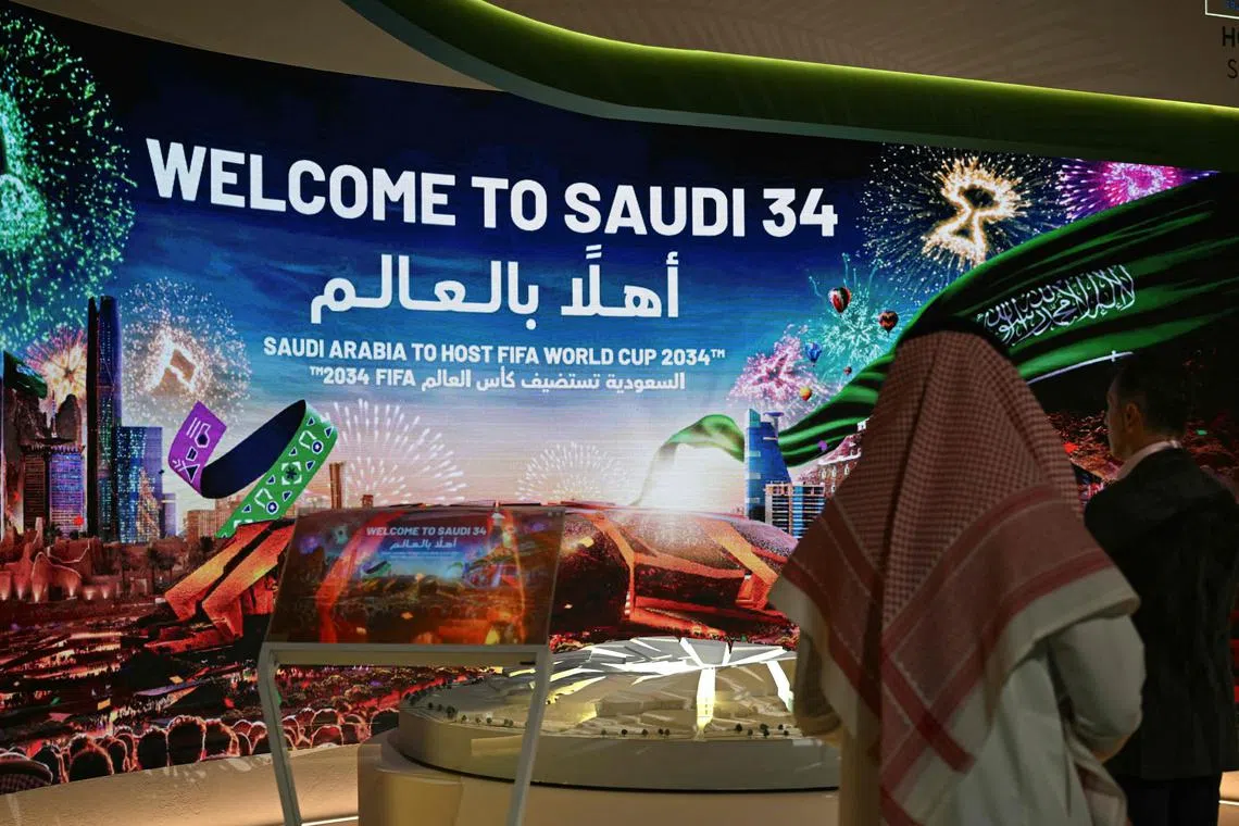 People walk past a stall displaying a welcome message for the Saudi 2034 FIFA World Cup football tournament at the Ministry of Media in Riyadh on May 13.