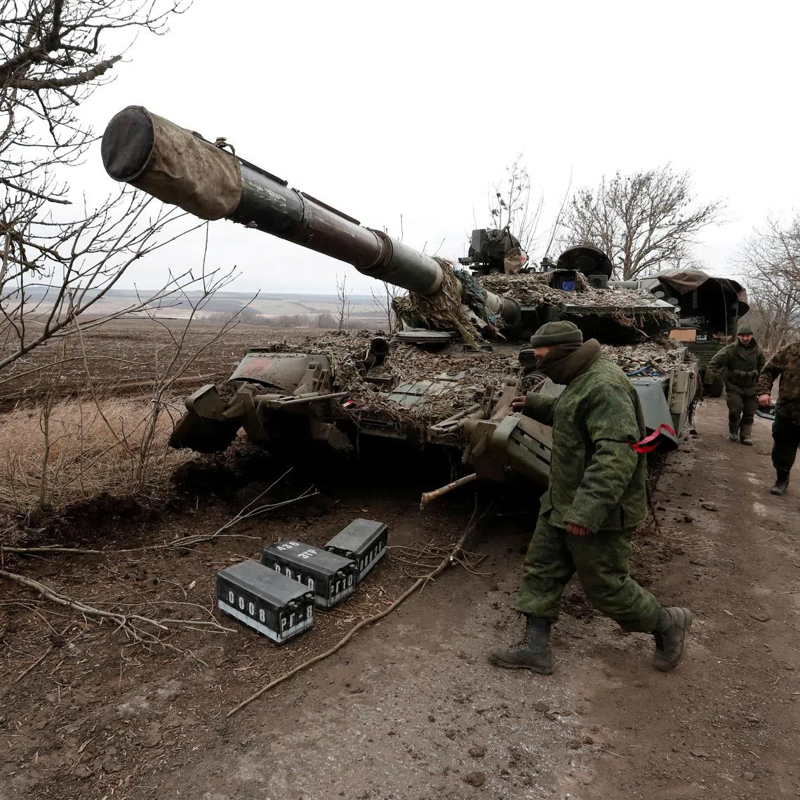 FILE PHOTO: Pro-Russian separatists walk near an abandoned tank on a road between the separatist-controlled settlements of Mykolaivka (Nikolaevka) and Buhas (Bugas), as Russia's invasion of Ukraine continues, in the Donetsk region, Ukraine March 1, 2022. REUTERS/Alexander Ermochenko/File Photo