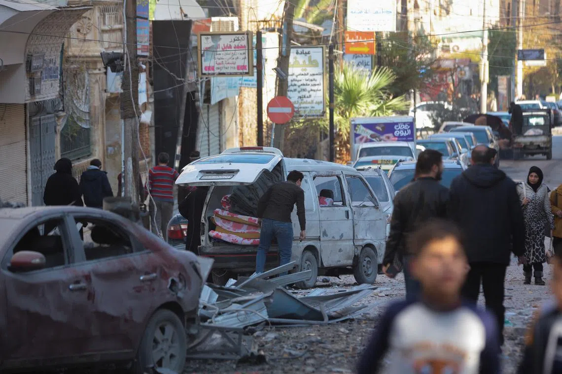 FILE PHOTO: People walk past a damaged site in Aleppo, after the Syrian army said that dozens of its soldiers had been killed in a major attack by rebels who swept into the city, in Syria November 30, 2024. REUTERS/Mahmoud Hassano/File photo