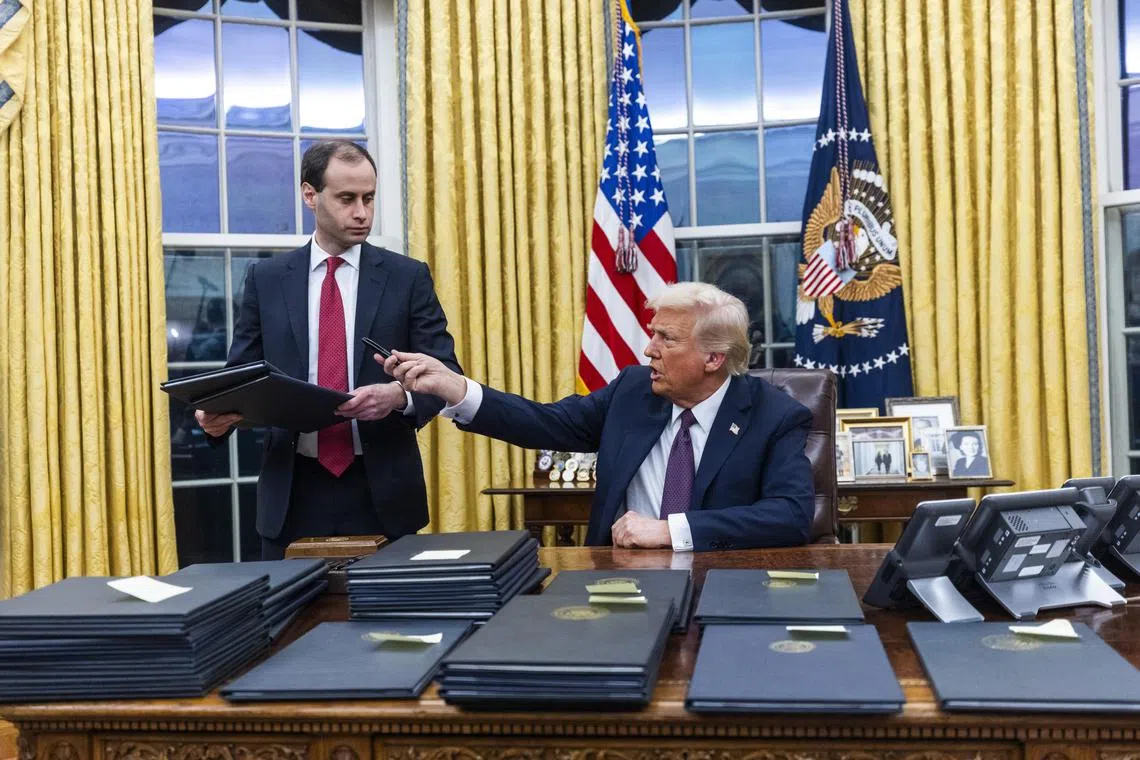 US President Donald Trump signing numerous executive orders on the first day of his presidency, on Jan 20.