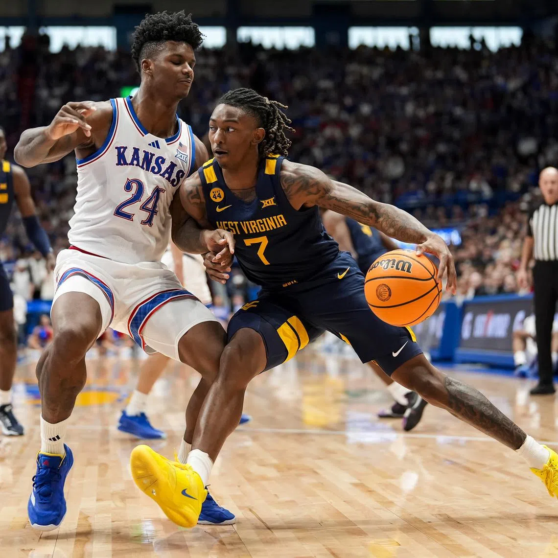 Dec 31, 2024; Lawrence, Kansas, USA; West Virginia Mountaineers guard Javon Small (7) drives against Kansas Jayhawks forward KJ Adams Jr. (24) during the first half at Allen Fieldhouse. Mandatory Credit: Jay Biggerstaff-Imagn Images