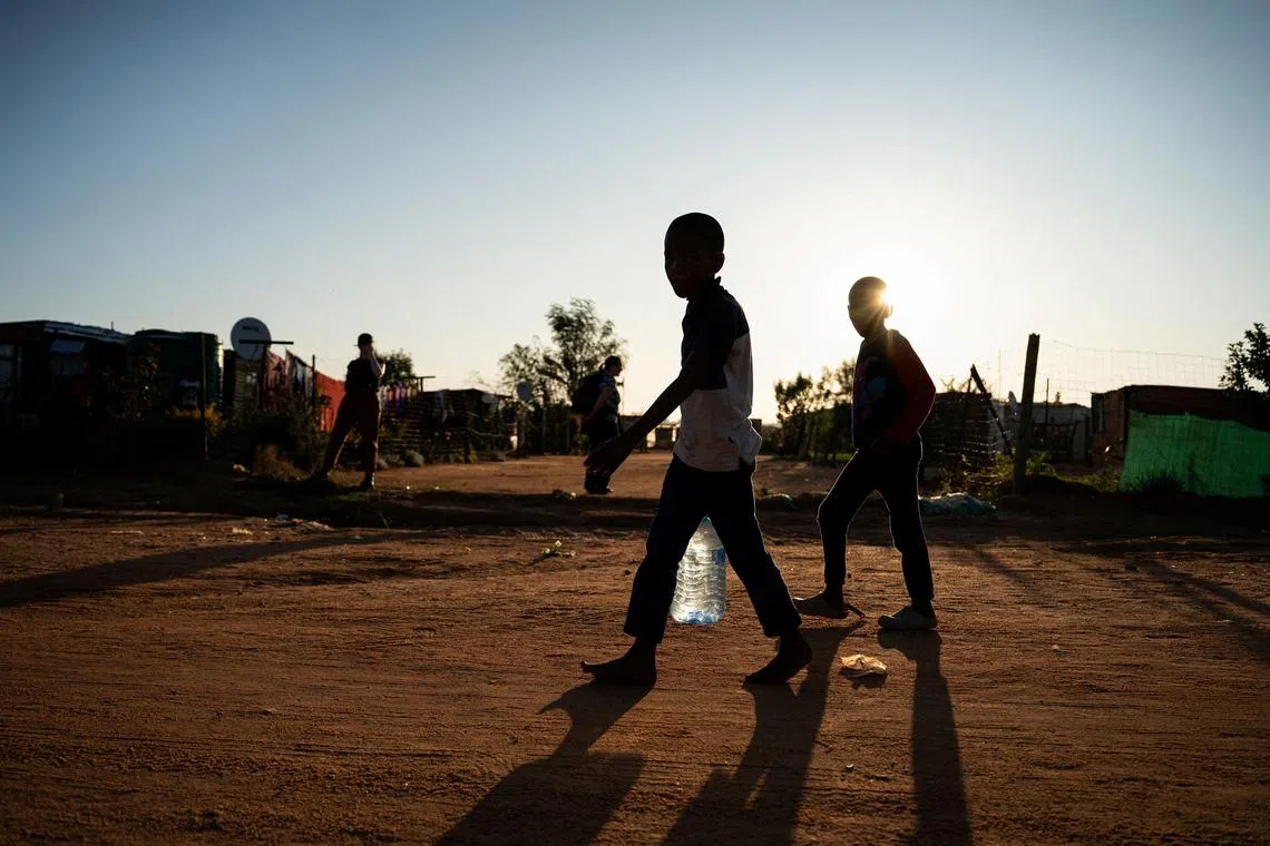 Young residents carry water home after filling up a bottle at a community filling station in the informal settlement of Kanana after individuals died from cholera in Hammanskraal, South Africa, May 24, 2023.  REUTERS/Ihsaan Haffejee     TPX IMAGES OF THE DAY