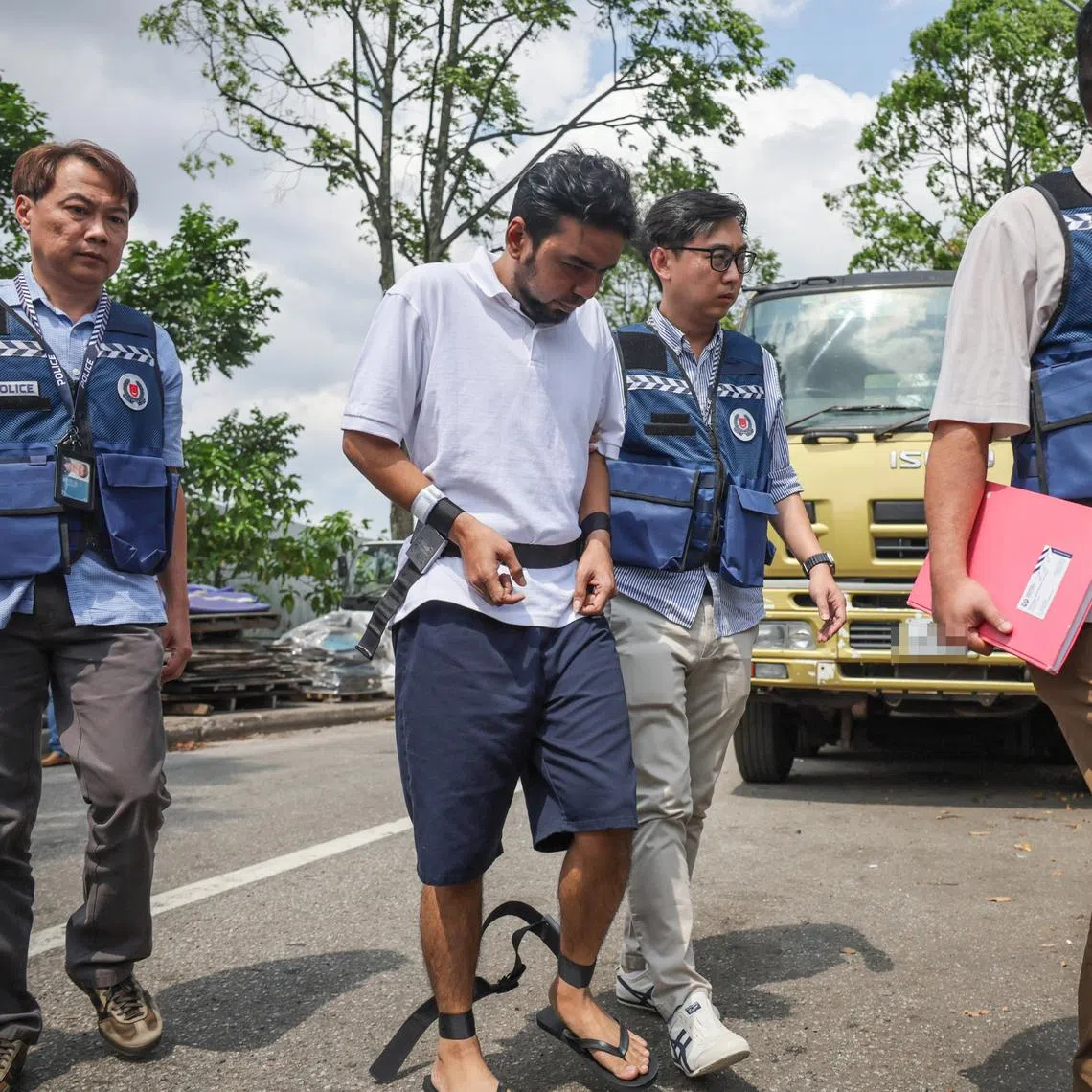 Mohd Mazuan Abdullah being escorted by police officers along Sungei Kadut street 4 to retrace his steps in a vehicle theft and car cloning syndicate in Malaysia, on March 23.
