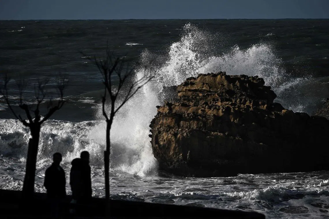 People watch waves at the central beach, in Biarritz, southwestern France, on February 11, 2024. In the Basque Country, with its 35 kilometres of sandy and rocky coastline, more than 500 individual and collective dwellings and around 40 businesses are threatened within 20 years by rising sea levels and their consequences, according to the "Communaute d'agglomeration". (Photo by Philippe LOPEZ / AFP)