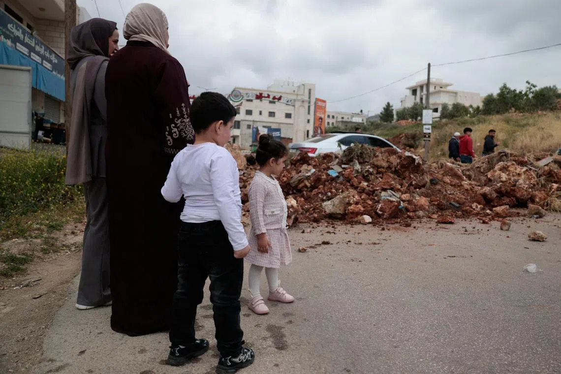 Palestinians standing next to a soil barrier, erected by the Israeli army, blocking an entrance to the village of Turmus Aya in the Israeli-occupied West Bank, on May 6, 2026. 