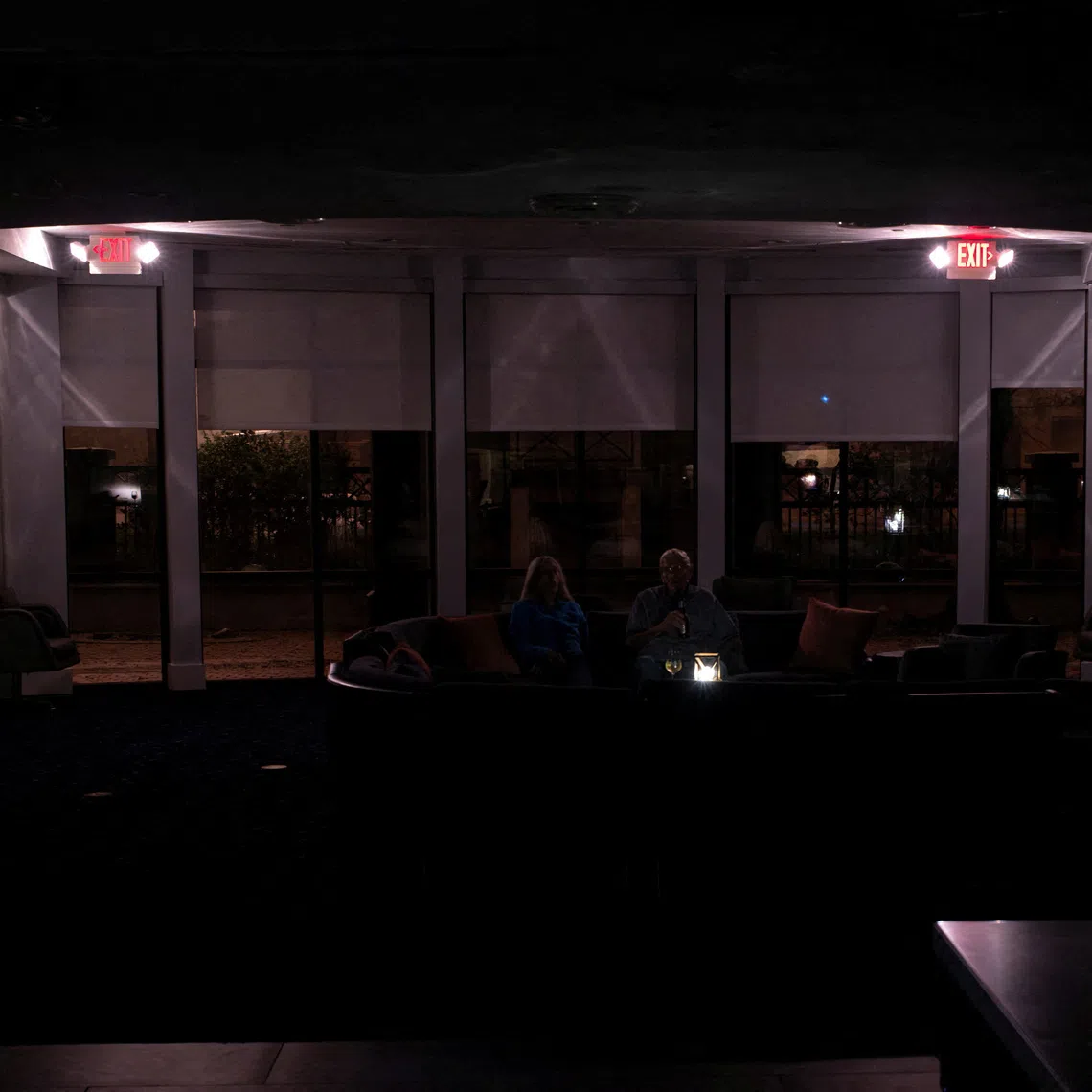 A couple have beers in a hotel lobby during a power outage ahead of the arrival of Hurricane Isaias, in Pensacola, Florida, US, October 9, 2026. REUTERS/Marco Bello