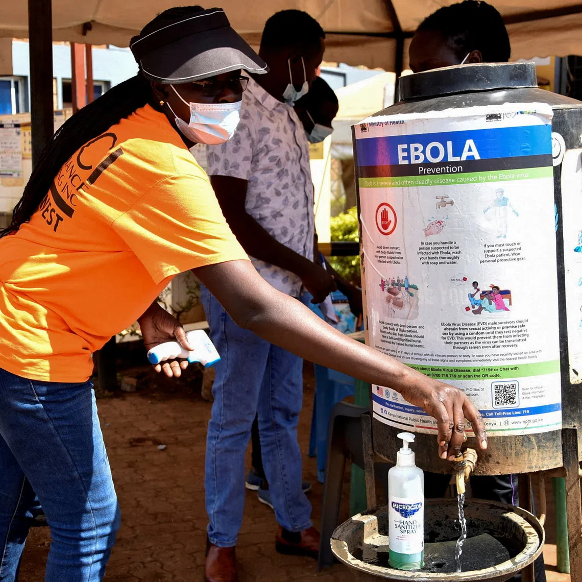 A medical worker controls the sanitisation point for travellers entering the Kenya immigration services from Uganda at a border post in Busia, Kenya, on Oct 8.