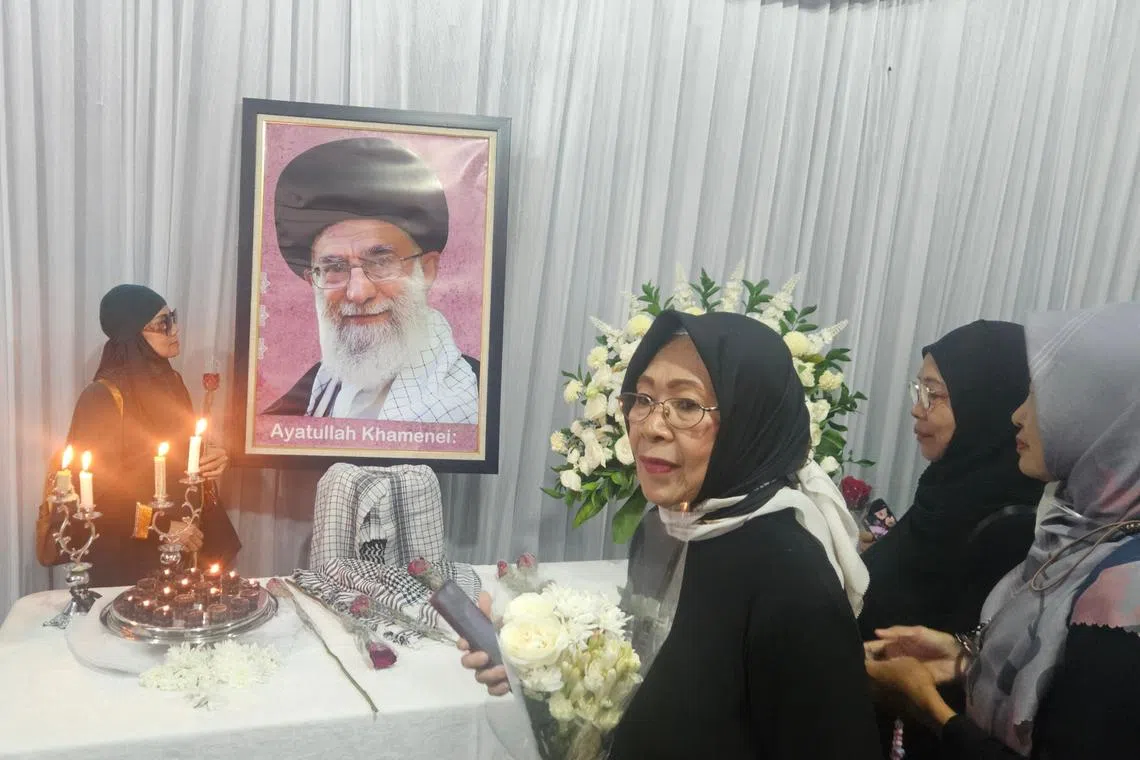 Mourners laid red and white flowers on a desk under a framed photo of Mr Khamenei.